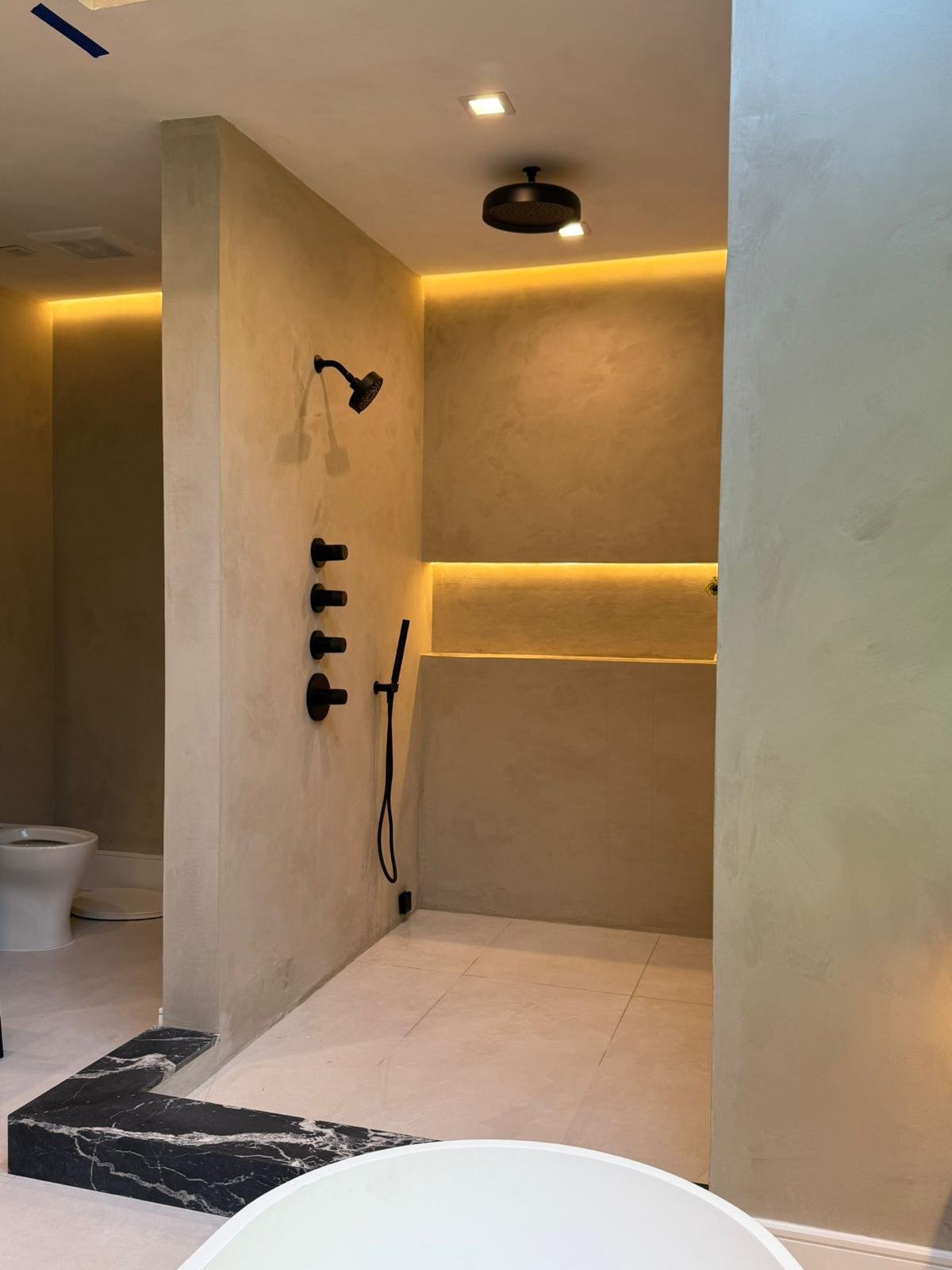 Warm cream microcement bathroom with black fixtures and LED cove, Williamsburg wet room — MarkOn® Walls / Vlad Markov