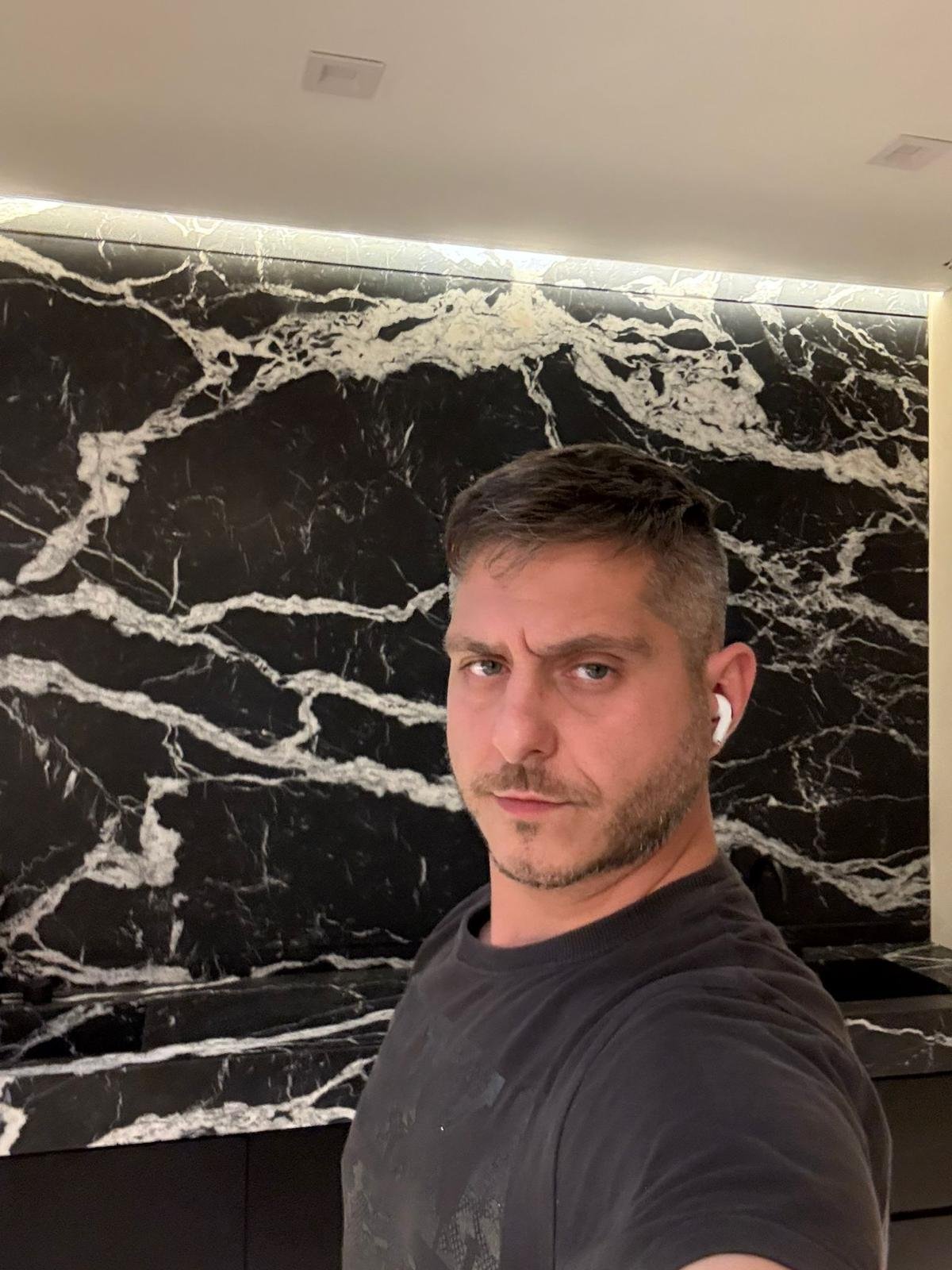 Vlad Markov — founder and master plasterer of MarkOn® Walls, against a hand-finished black marble feature wall, Greenpoint atelier